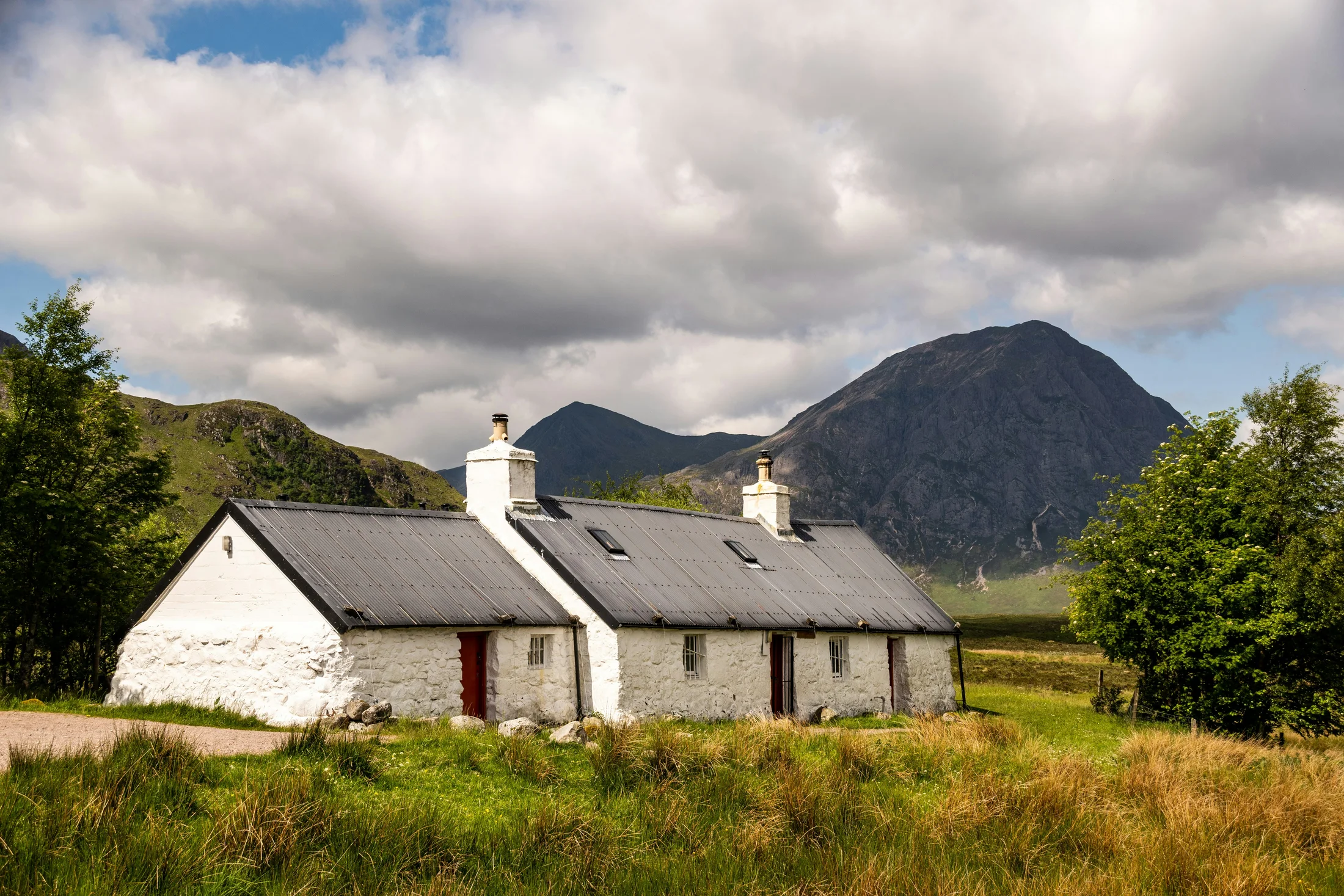 White cottage beneath a Highland mountain