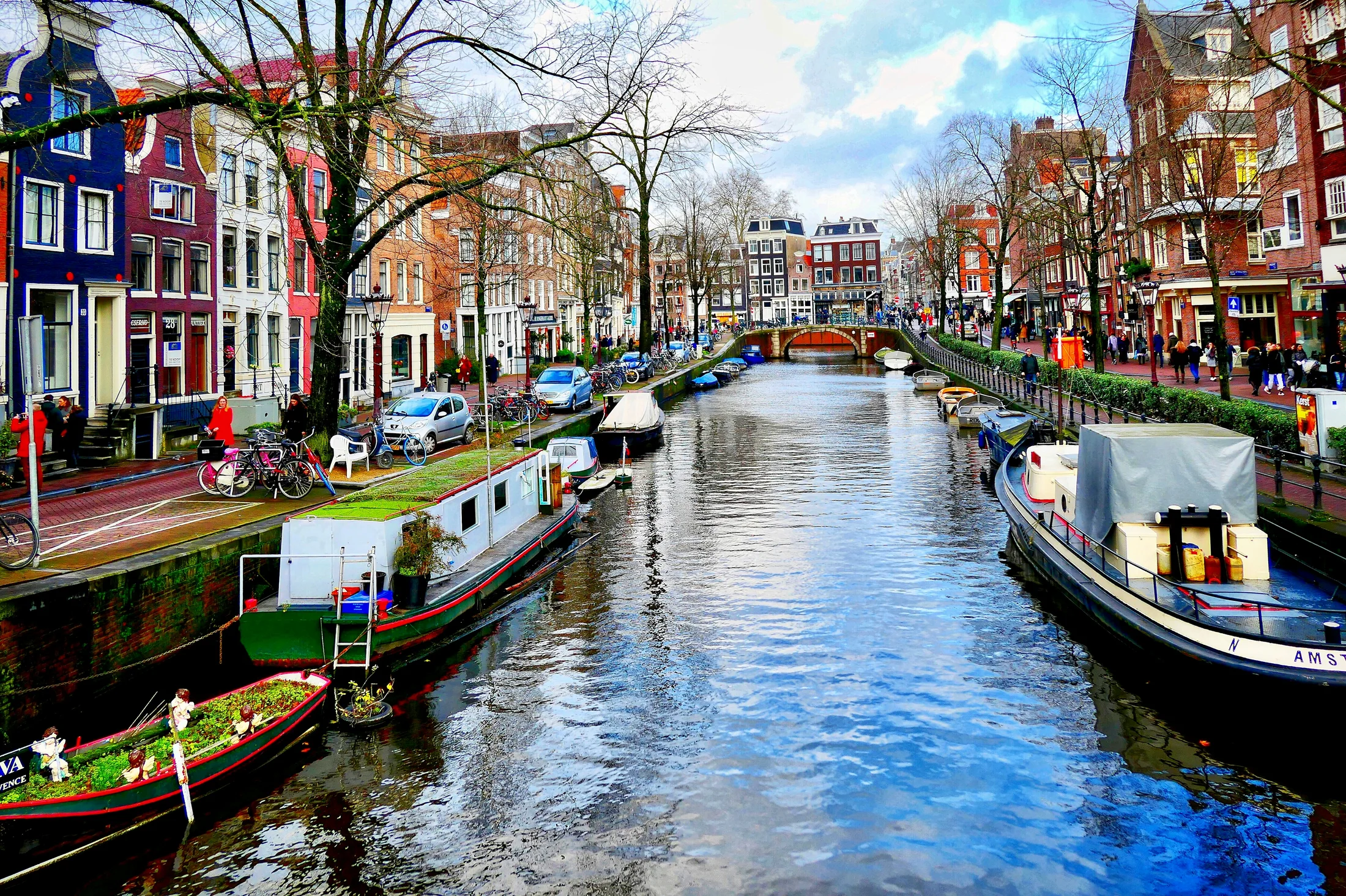 Amsterdam canal lined with boats, bicycles, trees, and brick houses