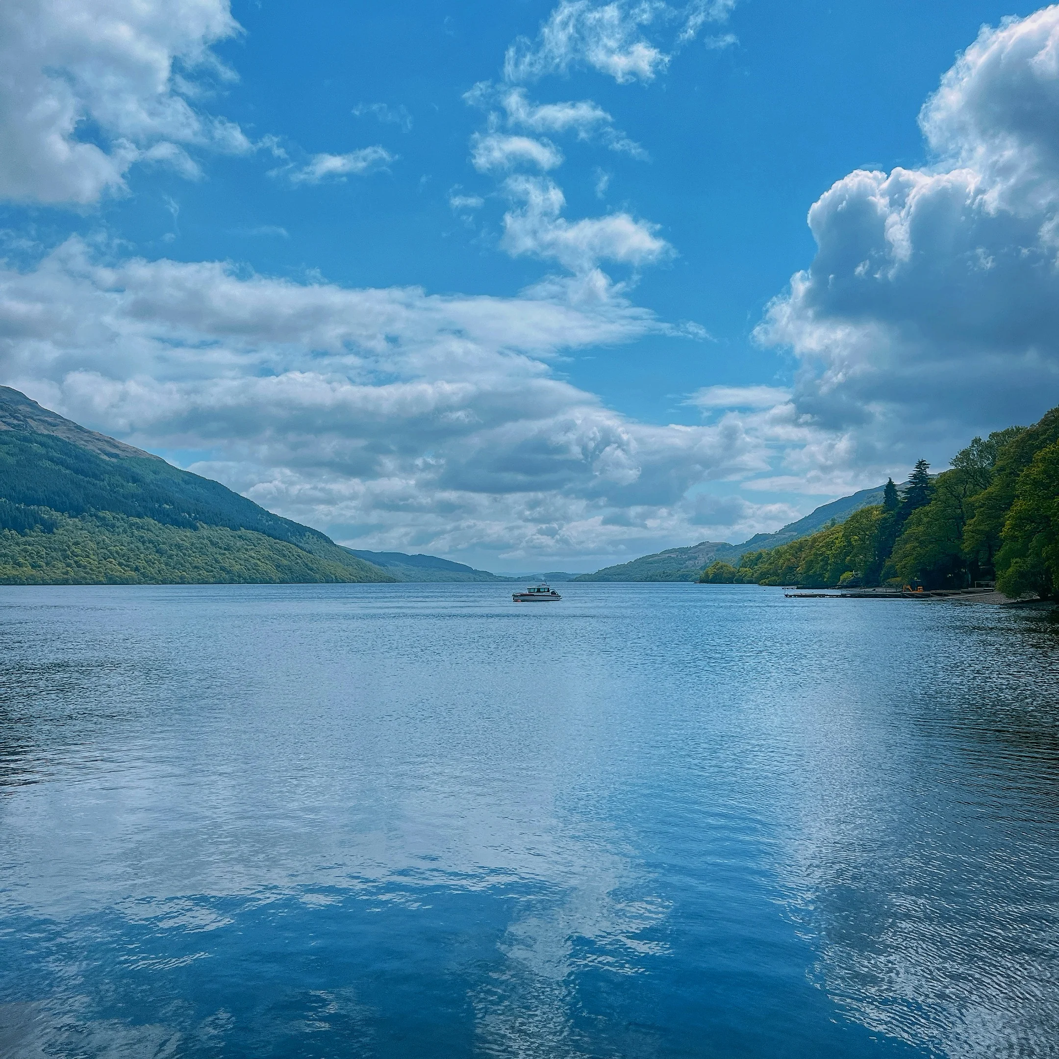 Boat on Loch Lomond beneath a bright sky