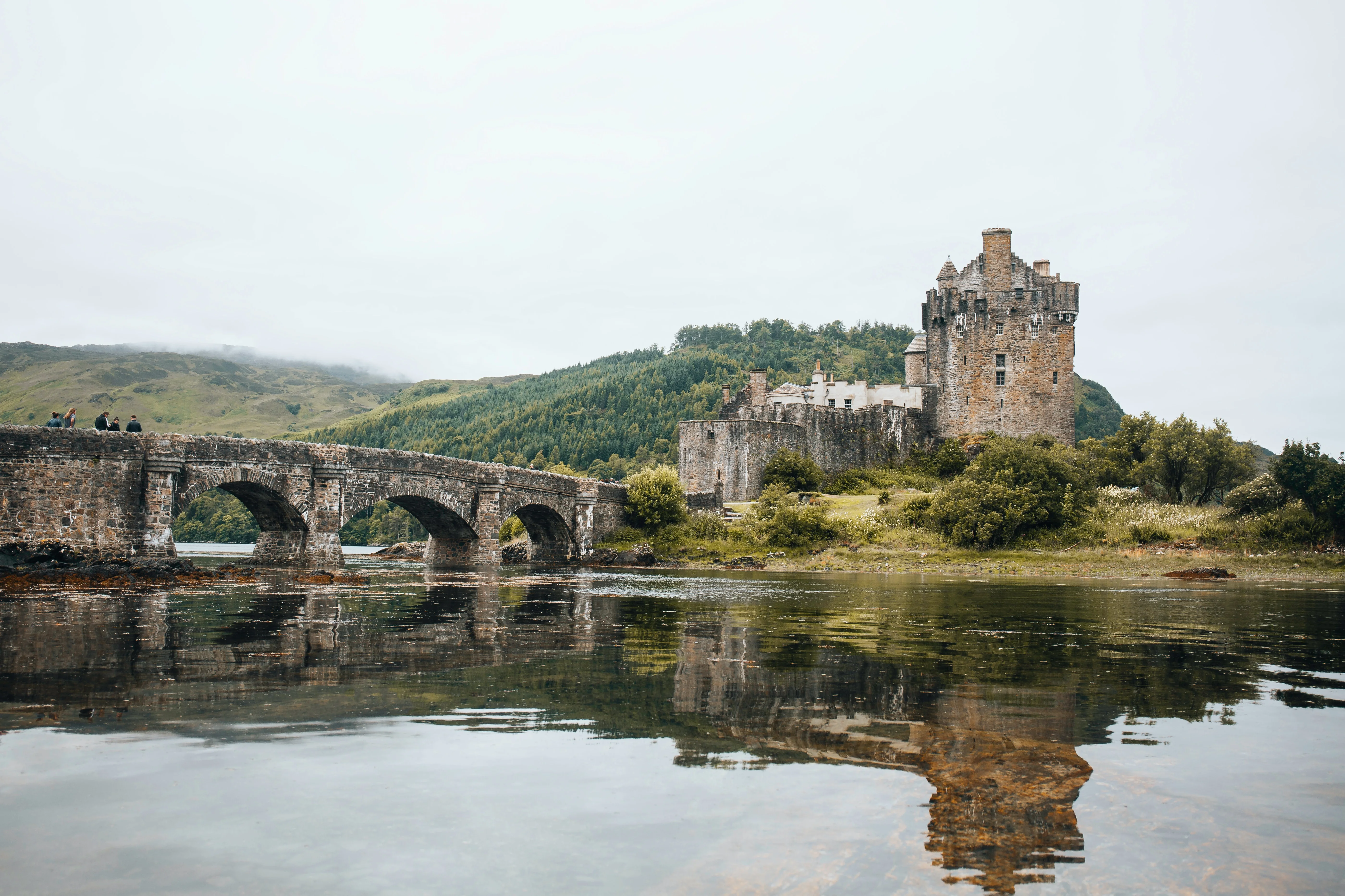 Historic castle and bridge reflected in water in the Scottish Highlands